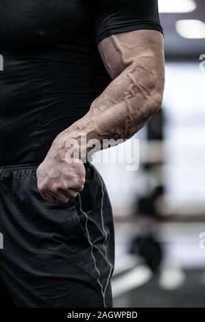 Körper Körperbau Teil der starke Mann in Schwarz Sportswear zeigt starke Arme mit großen Vene Stockfoto