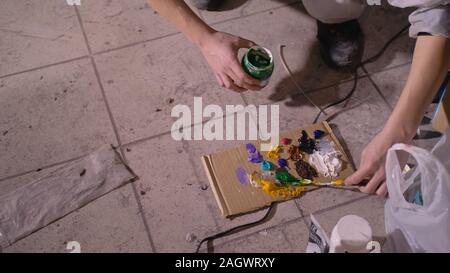 Künstler Designer zieht ein Adler an der Wand. Handwerker Dekorateur malt mit Acryl öl Farbe. Maler Maler gekleidet in Lack auftragen. Indoor. Stockfoto