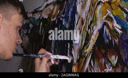 Künstler Designer zieht ein Adler an der Wand. Handwerker Dekorateur malt mit Acryl öl Farbe. Maler Maler gekleidet in Lack auftragen. Indoor. Stockfoto