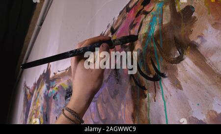 Künstler Designer zieht ein Adler an der Wand. Handwerker Dekorateur malt mit Acryl öl Farbe. Maler Maler gekleidet in Lack auftragen. Indoor. Stockfoto