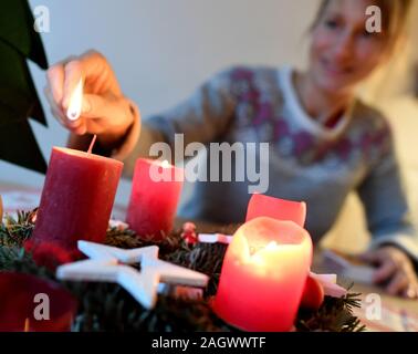 Garmisch Partenkirchen, Deutschland. 22 Dez, 2019. Abbildung - eine Frau, die Lichter der vierten Kerze am Adventkranz am vierten Advent. Quelle: Angelika Warmuth/dpa/Alamy leben Nachrichten Stockfoto