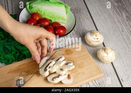 Frau schneiden Pilze auf Holzbrett Stockfoto