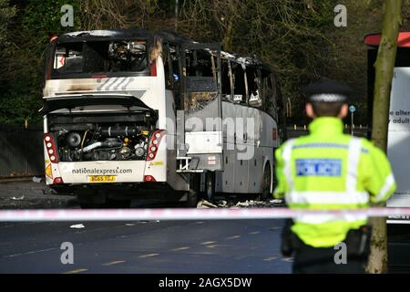 Ein Polizist sieht an an die verbrannten Überreste eines Trainers in Queenstown Road, South West London, nachdem eine Person getötet und drei andere wurden in eine Kollision zwischen dem Coach und ein Auto in den frühen Morgenstunden verletzt. Stockfoto