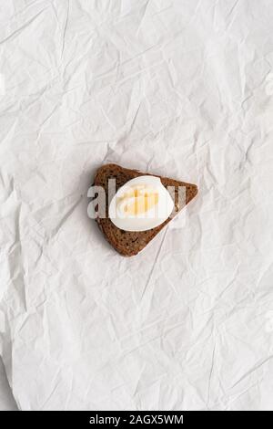 Die Hälfte gekochtes Ei auf einem dreieckigen Stück Brot Stockfoto