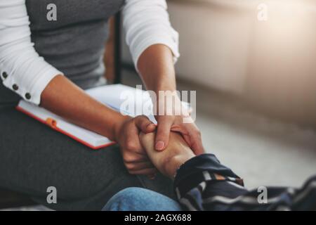 Frau Unterstützung und Hilfe. Frauen halten einander die Hände sitzen in der modernen Loft Büro Stockfoto