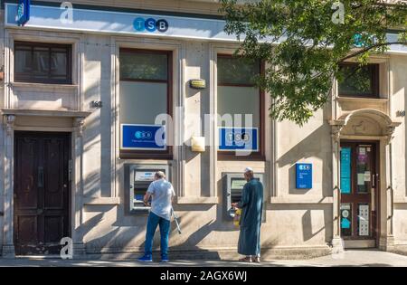 Zwei Männer machen Bargeldabhebungen an Geldautomaten außerhalb einer Niederlassung der TSB Bank auf einer sonnigen und ruhigen Morgen. High Street, Acton, London, W3, England, UK. Stockfoto