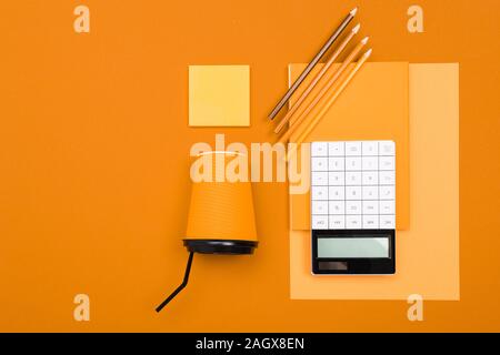 Schul- und Büromaterial liegen fein säuberlich auf einen orangen Hintergrund Stockfoto