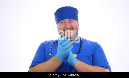 Bärtige lächelnd männlichen medizinischer Arbeiter in blauer Kleidung klatscht in die Hände. Stockfoto