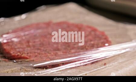 Kochen macht Fleisch Medaillons für Burger. Koch in schwarz Handschuhe macht Schnitzel essen. Die koteletts sind in Stahl Ring in eine noch Medaillon eingeebnet. Stockfoto