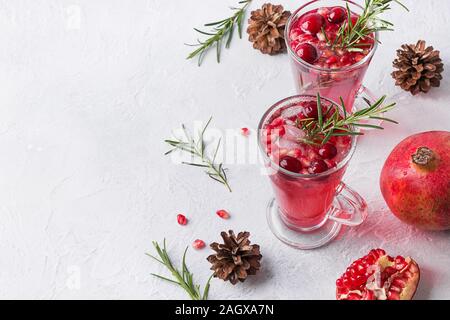 Zwei Glas Granatapfel Weihnachten Cocktail mit Rosmarin, Moosbeere, Sekt auf weißer Tisch. Xmas trinken. Platz für Text. Stockfoto