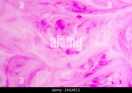 Ein Makro Foto von Tropfen pink Lebensmittelfarbe wirbelte und gemischt in dicken, cremigen weiße Milch Eine marmorierte Milchshake Effekt zu geben Stockfoto