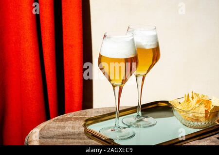 Bier in Flöte, Pils oder Pilsner, mit Tortilla-Chips, heller bunter Hintergrund Stockfoto