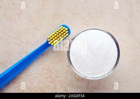 Zahnbürste und Backpulver in eine Schüssel geben. Alternative Zahnpasta und Zahnpflege. Ansicht von oben. Stockfoto