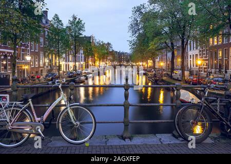 Amsterdam, Niederlande - 16.10.2019: Amsterdam Canal mit Fahrrädern auf der Brücke am Abend. Stockfoto