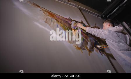 Künstler Designer zieht ein Adler an der Wand. Handwerker Dekorateur malt mit Acryl öl Farbe. Maler Maler gekleidet in Lack auftragen. Indoor. Stockfoto