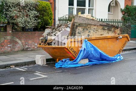 Große orange Metall überspringen Container vor Haus, voller Müll von Haushalt Wiederaufbau Stockfoto