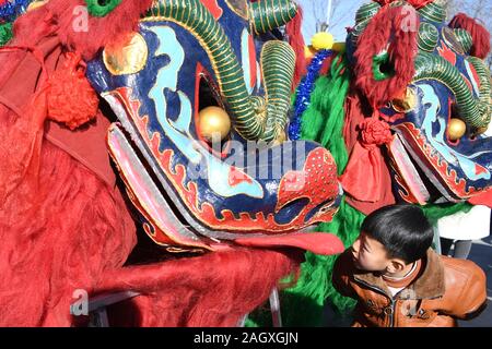 Yongdeng, China. 22 Dez, 2019. Yongdeng (Gansu. 22 Dez, 2019. Ein Junge schaut auf den Kopf des Löwen Tanz Kostüm in Yongdeng County, Lanzhou, der Hauptstadt der Provinz Gansu im Nordwesten Chinas, Dez. 22, 2019. Lion Dance ist eine traditionelle darstellende Kunst Chinas. Yongdeng Lion Dance, ein lokaler Stil von Lion Dance für seine unverwechselbare und komplizierte Bewegung bekannt, wurde als die immateriellen Kulturerbes der Provinz Gansu im Jahr 2011 aufgeführt. Der Löwe Kostüm, von Holzleisten im Inneren, ist etwa 2,8 Meter lang und 1,8 Meter hoch, so dass der Tanz eine anspruchsvolle Aufgabe für Künstler unterstützt. Credit: Xinhu Stockfoto