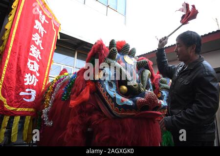 Yongdeng, China. 22 Dez, 2019. Ein volkskünstler reinigt das Kostüm für die Lion Dance Rehearsal in Yongdeng County, Lanzhou, der Hauptstadt der Provinz Gansu im Nordwesten Chinas, Dez. 22, 2019. Lion Dance ist eine traditionelle darstellende Kunst Chinas. Yongdeng Lion Dance, ein lokaler Stil von Lion Dance für seine unverwechselbare und komplizierte Bewegung bekannt, wurde als die immateriellen Kulturerbes der Provinz Gansu im Jahr 2011 aufgeführt. Der Löwe Kostüm, von Holzleisten im Inneren, ist etwa 2,8 Meter lang und 1,8 Meter hoch, so dass der Tanz eine anspruchsvolle Aufgabe für Künstler unterstützt. Quelle: Xinhua/Alamy leben Nachrichten Stockfoto