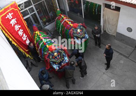 Yongdeng, China. 22 Dez, 2019. Yongdeng (Gansu. 22 Dez, 2019. Folk Künstler machen Sie sich bereit für die Lion Dance Rehearsal in Yongdeng County, Lanzhou, der Hauptstadt der Provinz Gansu im Nordwesten Chinas, Dez. 22, 2019. Lion Dance ist eine traditionelle darstellende Kunst Chinas. Yongdeng Lion Dance, ein lokaler Stil von Lion Dance für seine unverwechselbare und komplizierte Bewegung bekannt, wurde als die immateriellen Kulturerbes der Provinz Gansu im Jahr 2011 aufgeführt. Der Löwe Kostüm, von Holzleisten im Inneren, ist etwa 2,8 Meter lang und 1,8 Meter hoch, so dass der Tanz eine anspruchsvolle Aufgabe für Künstler unterstützt. Credit: Xin Stockfoto