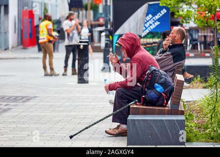 Montreal, Kanada - Juni, 2018: Zwei kanadische obdachlose Männer auf der Bank sitzen und rauchen eine Zigarette. Stockfoto