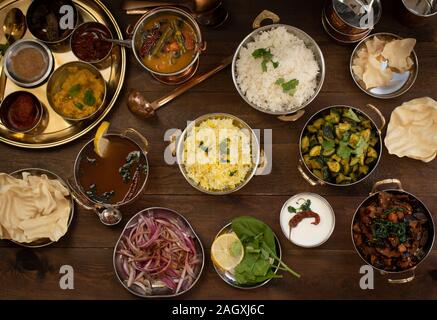 Vielzahl von Süden indische Gerichte auf einen hölzernen Tisch serviert in der traditionellen copperware Stockfoto