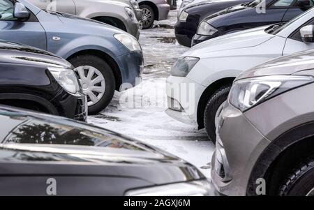 Autos im Schnee geparkten überdachter Parkplatz, nur Details am vorderen Stoßfänger Scheinwerfer und Reifen Stockfoto