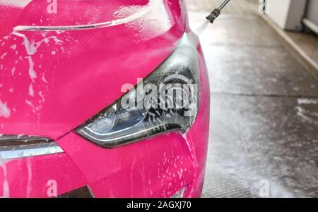 Anzeigeleuchte vorne Rosa Auto in selbst gewaschen dienen Carwash, Jet Wasser spritzen auf transparente Kunststoffe Stockfoto