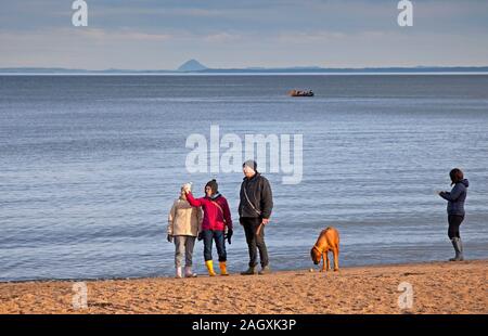 Portobello Beach, Edinburgh, Schottland, Großbritannien. Dezember 2019. Kühle Temperatur von 4 Grad mit wenig Sonnenschein an der Küste ermutigend Menschen, die frische Luft entlang des Sandstrandes genießen und den Hund zu Fuß. Berwick Law im Hintergrund. Stockfoto