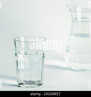 Reine klare Wasser in ein Glas Glas und Glas Krug steht auf einem weißen Hintergrund Stockfoto