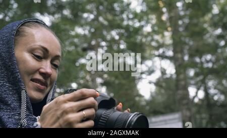 Traveler fotografieren malerischen Blick in den Wald. Eine kaukasische Frau schießen aus der Nähe betrachten. Mädchen nehmen Foto Video auf dslr spiegellosen Kamera. Stockfoto