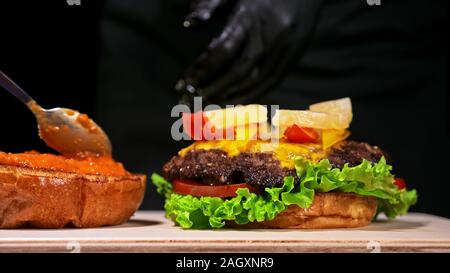 Handwerk Burger ist Kochen. Bestehen: rote Sauce salsa, Salat, rote Zwiebel, Gurke, Käse, Chili, Paprika, Bun- und marmoriertes Fleisch Rindfleisch. Stockfoto