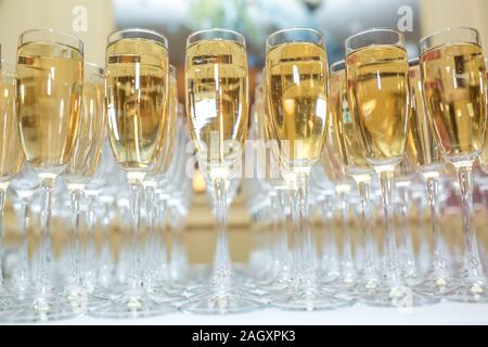 Menge unscharfer Gläser mit Champagner auf der Rezeption Partei Tabelle auf hellen Hintergrund Stockfoto