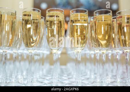 Menge unscharfer Gläser mit Champagner auf der Rezeption Partei Tabelle auf hellen Hintergrund Stockfoto