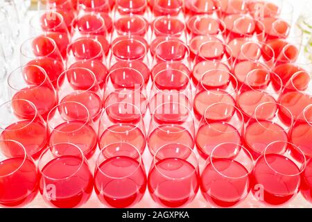 Menge unscharfer Gläser mit Rotwein auf der Rezeption Partei Tabelle auf hellen Hintergrund Stockfoto