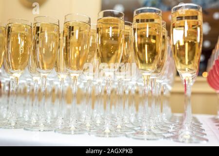 Menge unscharfer Gläser mit Champagner auf der Rezeption Partei Tabelle auf hellen Hintergrund Stockfoto
