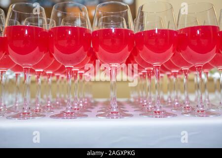Menge unscharfer Gläser mit Rotwein auf der Rezeption Partei Tabelle auf hellen Hintergrund Stockfoto