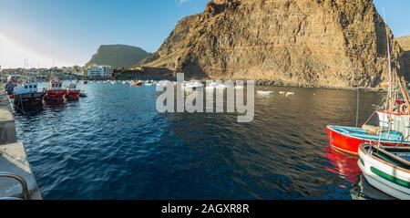 Breites Panorama von Playa De Vueltas Strand und Hafen mit Yachten und Fischerboote am Atlantischen Ozean in La Gomera. Ein beliebter Urlaubsort für Touristen Stockfoto