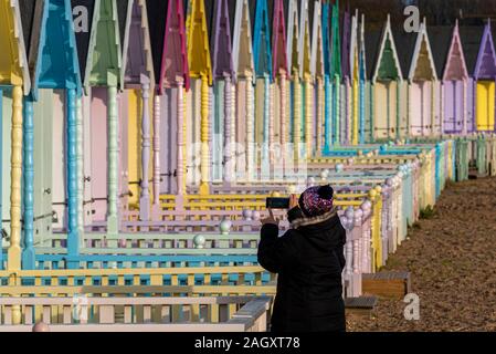 West Mersea, mersea Island, Essex, Großbritannien. Die nassen bewölkten Morgen brach in einem hellen, aber sehr kalten Nachmittag auf mersea Island in der Nähe von Colchester, Essex, an. Auf dem Fluss Blackwater Estuary. Weibliche Fotografieren von den bunten Badekabinen Stockfoto