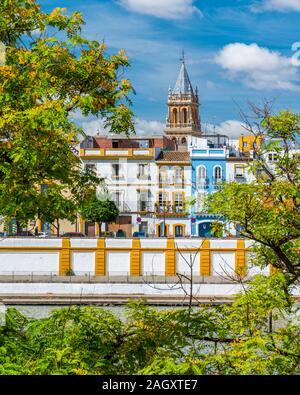 Farbenfrohen Anblick entlang des Flusses Guadalquivir in Sevilla, mit dem Glockenturm der echten Parroquia de Senora Santa Ana. Andalusien, Spanien. Stockfoto