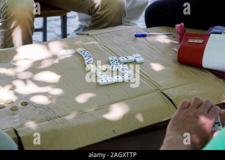 Berat, Albanien, 9. Juli 2019: Alte Männer spielen das Spiel Domino in Berat im Schatten der Bäume. In der Nähe von Dominos Stockfoto