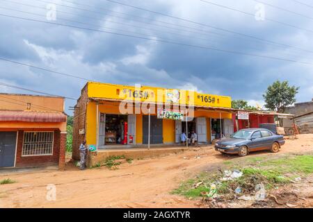 Typische Flachbau am Straßenrand Dorf Geschäfte, Schönheitssalon und Gebäude für die Menschen vor Ort in der westlichen Region von Uganda, an einem bewölkten Tag Stockfoto