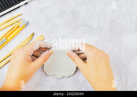 Ton Schüssel Thema dekorieren, Töpferei. Das Schnitzen von handgemachtem Geschirr mit speziellen Werkzeugen Stockfoto