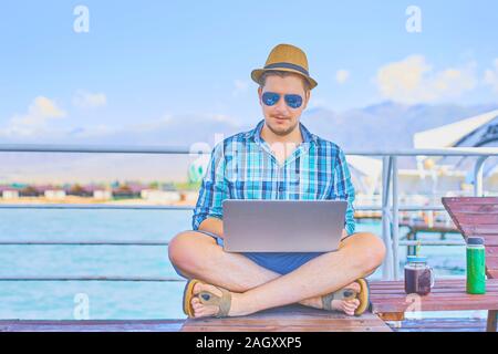 Junge Unternehmer ruht auf den Piers, genießen Sommer in Resort Spa in der Nähe von Meer, während remote Arbeiten am Laptop mit Wireless interne angeschlossen Stockfoto