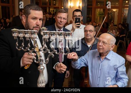 Bremen, Deutschland. 22 Dez, 2019. Rabbiner Natanel Teitelbaum (L) leuchtet eine Chanukka Kerze zusammen mit Holocaust-überlebenden Grigori Skoblov (90) an der Chanukka Feier im jüdischen Gemeindezentrum in Bremen anlässlich des "Internationalen Überlebenden 'Nacht' von der Jewish Claims Conference. Die Zeremonie zu Ehren der Überlebenden des Holocaust wird auch in München, New York, Moskau, Paris und Jerusalem statt. Quelle: Jörg Sarbach/dpa/Alamy leben Nachrichten Stockfoto