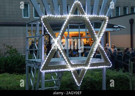 Bremen, Deutschland. 22 Dez, 2019. Mitglieder der Jüdischen Gemeinde Bremen Spaziergang, vorbei an einem beleuchteten Stern von David in der Community Center. Dort feiern die "Internationale Nacht der Überlebenden" der Jewish Claims Conference als Teil der Chanukka Feier. Die Zeremonie zu Ehren der Überlebenden des Holocaust wird auch in München, New York, Moskau, Paris und Jerusalem statt. Quelle: Jörg Sarbach/dpa/Alamy leben Nachrichten Stockfoto