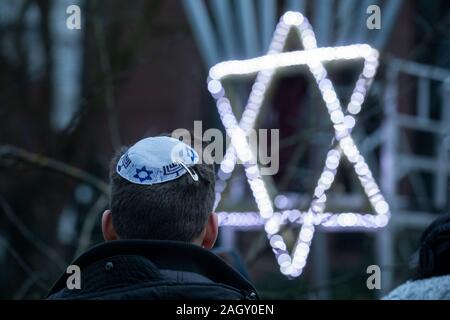 Bremen, Deutschland. 22 Dez, 2019. Anlässlich des "Internationalen Überlebenden 'Nacht' von der Jewish Claims Conference für die chanukka Feier vor der Jüdischen Gemeinde Zentrum, ein junger Jude vor einer beleuchteten David Stern steht. Die Zeremonie zu Ehren der Überlebenden des Holocaust wird auch in München, New York, Moskau, Paris und Jerusalem statt. Quelle: Jörg Sarbach/dpa/Alamy leben Nachrichten Stockfoto