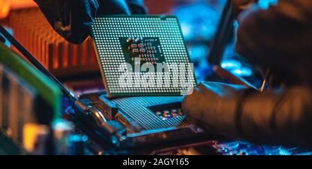 Ingenieur Mechaniker Hände halten in schwarz Handschuhe, Prozessor, CPU in den Sockel des computer Motherboard zu stecken. Konzept der Technologie hart Stockfoto