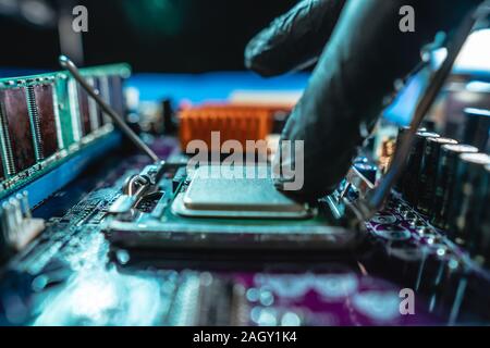 Ingenieur Mechaniker Hände halten in schwarz Handschuhe, Prozessor, CPU in den Sockel des computer Motherboard zu stecken. Das Konzept der Technologie Stockfoto