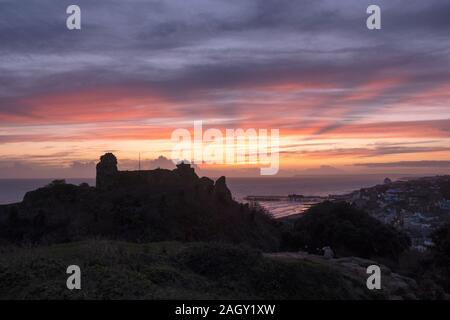 Hastings, East Sussex, Großbritannien. Dezember 2019. Farbenprächtiger Sonnenuntergang auf Schloss Hastings am kürzesten Tag des Jahres. Wintersonnenwende. Stockfoto