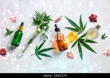 Glasflaschen mit CBD Öl, Hanf Blätter in Weihnachten Dekoration. Festliche Hintergrund für Cannabis Flach Stockfoto